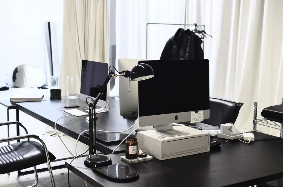 Un espace de travail moderne avec deux écrans d’ordinateur affichant des projets de web design, mettant en avant la technologie et la productivité.